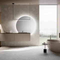Bagni moderni con eleganti piastrelle effetto pietra. Vasca ovale, mobile sospeso e specchio luminoso creano un'oasi di relax.
