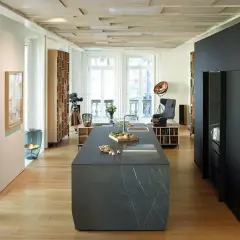 Cucina moderna con isola in pietra, parquet chiaro e dettagli in cementine.