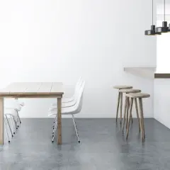 Tavolo in legno con sedie bianche e sgabelli al bancone, su un elegante **pavimento senza fughe**.