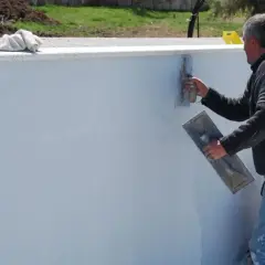 Operaio stende malta bastarda su un muro. Questo materiale serve per intonaci e murature, garantendo resistenza e durabilità.