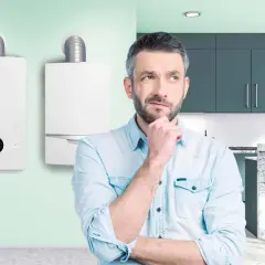 Uomo pensieroso davanti a due caldaie, una delle quali è una caldaia turbo Bosch.