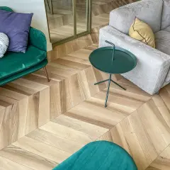 Un elegante soggiorno con un pavimento stile nordico a spina di pesce. Divani verdi e grigi, tavolino verde e cuscini decorativi.