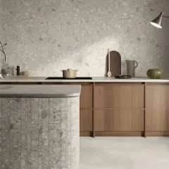 Cucina moderna con isola in **ceppo di gre** e rivestimenti a parete in grès effetto terrazzo.