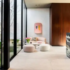 Un elegante soggiorno con pavimenti in marmo moderni, divano rosa, pouf e un tavolino bianco.