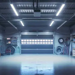 Illuminazione garage consigli: un interno ben illuminato con luci a soffitto, porte chiuse, armadi e attrezzi.