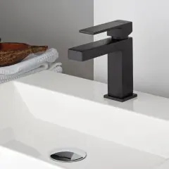 Lavabo bianco moderno con rubinetteria nera opaca. Accanto, asciugamani bianchi e una ciotola con prodotti da bagno.