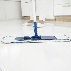 Pulizia finale del pavimento bianco dopo la ristrutturazione. Un mocio pulisce le piastrelle lucide, lasciando una finitura impeccabile.