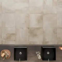 Bagno moderno con due lavabi neri, accessori e un rivestimento in gres tutta massa effetto pietra.