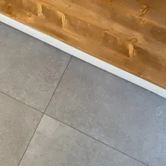 Le piastrelle grigie con venature sottili si incontrano sotto un piano in legno scuro, creando un contrasto moderno.