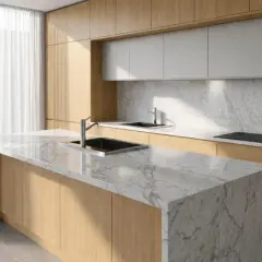 Cucina moderna con isola centrale e piano in marmo bianco venato. Ante in legno chiaro e schienale in marmo completano l'ambiente.