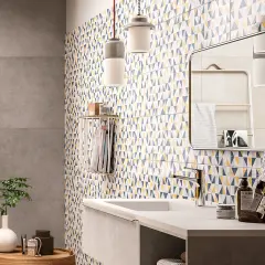 Un bagno moderno con piastrelle geometriche colorate che coprono le pareti. Un lavandino minimalista e un grande specchio completano l'arredo.