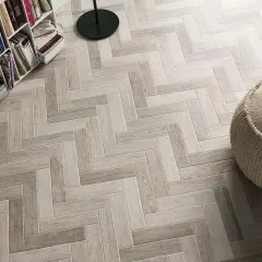 Un elegante pavimento ruvido interno in parquet a spina di pesce, con una libreria e un pouf.