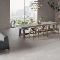 Un elegante soggiorno con divano grigio, tavolo da pranzo in cemento e sedie in legno, il tutto su un pavimento in gres porcellanato ruvido che evoca un'atmosfera moderna e accogliente.