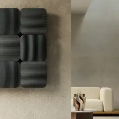 Nove pannelli grigi con finitura a coste, che sembrano termosifoni ad alto rendimento termico, montati su una parete grezza.