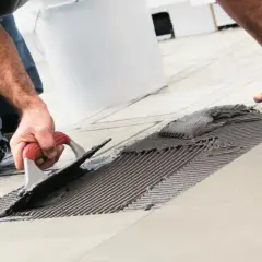 Operaio con spatola stende colla per il montaggio piastrelle.