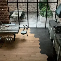 Un'elegante cucina con pavimenti che uniscono il calore del **parquet** e il design moderno delle **maioliche** esagonali scure.