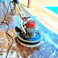 Macchina lavapavimenti in azione su un deck di legno, rimuovendo efficacemente la polvere di muratura e lo sporco, vicino a una piscina.