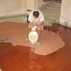 Uomo versa resina per coprire piastrelle cucina, creando una superficie lucida e moderna.