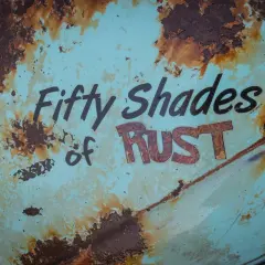 Superficie metallica sbiadita con scritte "Fifty Shades of RUST". La ruggine, che sembra voler togliere il colore originale, crea un effetto visivo intenso.