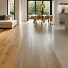 Un elegante soggiorno con divano e tavolo da pranzo si apre su una cucina moderna. L'effetto pavimento crea una transizione fluida tra le aree, con doghe in legno chiaro e un rivestimento in resina chiara.