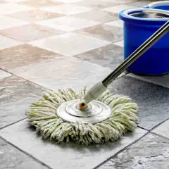 Mocio su pavimento in cotto, pronto per pulire il terrazzo. Secchio blu sullo sfondo.