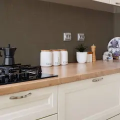Fornelli neri su piano in legno, con barattoli per zucchero, tè e caffè. Sfondo con piastrelle effetto vernice per piastrelle cucina.