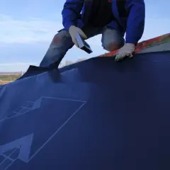 Installazione di una barriera al vapore su un tetto. La scheda tecnica del materiale è visibile.