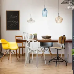 Tavolo da pranzo con sedie colorate e moderne, illuminato da lampade a sospensione. Ideale per chi vuole spostare punto luce soffitto e creare un ambiente accogliente.
