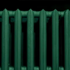 Un termosifone in ghisa, appena verniciato di un verde scuro e profondo, pronto a scaldare l'ambiente.