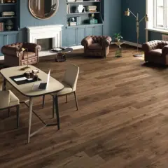 Un elegante soggiorno con camino, poltrone in pelle e un tavolo da lavoro. Il pavimento in legno scuro, perfetto per la posa pavimenti, completa l'arredamento.