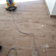 Macchina levigatrice in azione per rimuovere la patina bianca sul pavimento in finto legno.