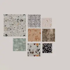 Vari campioni di piastrelle con un affascinante **effetto graniglia** in diverse colorazioni e dimensioni, dal bianco al nero, passando per tonalità naturali e pastello.