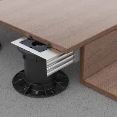 Dettaglio di un pavimento appoggiato su supporti regolabili neri, con finitura effetto legno marrone e profili metallici.