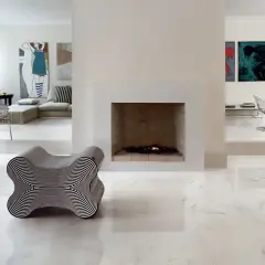 Pavimento rettificato: pro e contro. Un salotto moderno con camino, opere d'arte e un particolare divano a forma di osso.