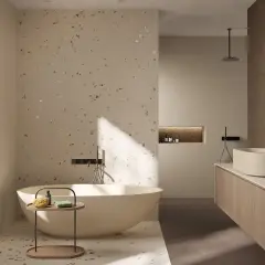 Bagno moderno con vasca freestanding e lavabo su mobile sospeso. Pareti e pavimento in fap gres porcellanato effetto terrazzo con inserti metallici.