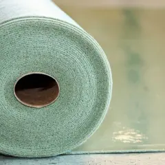 Rotolo di materiale per insonorizzare pavimento, con texture fibrosa e colore verde chiaro.