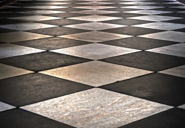 Pavimento a scacchi con posa piastrelle in diagonale, alternando marmo bianco e nero.