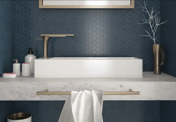 Un elegante bagno con un lavabo rettangolare bianco su un piano in marmo. Le pareti sono rivestite con un bellissimo posa mosaico esagonale blu scuro.
