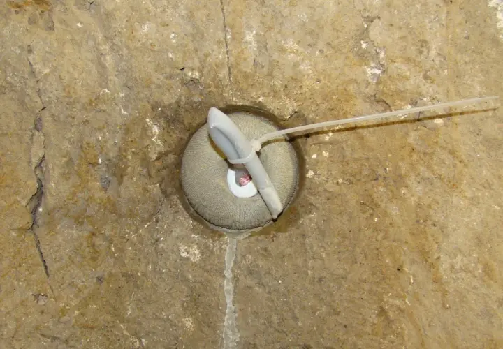 Dettaglio di un foro in muratura con un inserto in tessuto e un tubo, forse per il drenaggio o per i diatoni muratura.