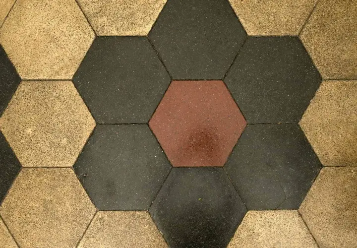 Pavimentazione a nido d'ape con cementine esagonali color ocra, grigio scuro e un tocco di rosso.