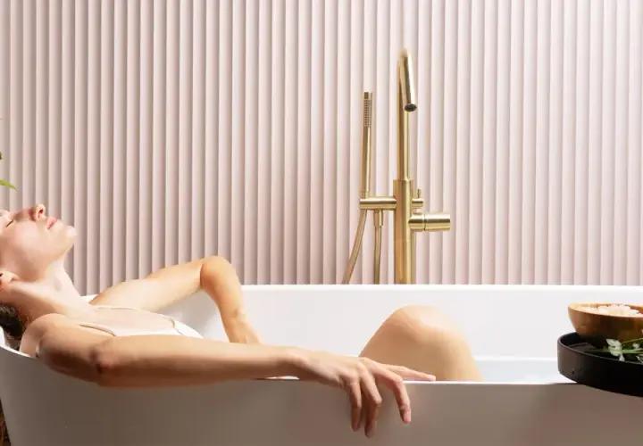 Donna rilassata in una vasca da bagno, creando un'atmosfera da bagno effetto spa con candele e fiori.