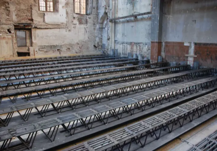 Strutture metalliche a traliccio pronte per essere posizionate per come rinforzare un solaio da sotto. L'ambiente è in fase di ristrutturazione.