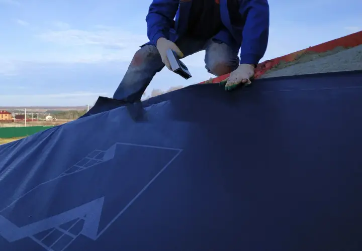 Installazione di una barriera al vapore su un tetto. La scheda tecnica del materiale è visibile.