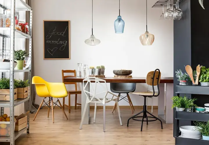 Tavolo da pranzo con sedie colorate e moderne, illuminato da lampade a sospensione. Ideale per chi vuole spostare punto luce soffitto e creare un ambiente accogliente.