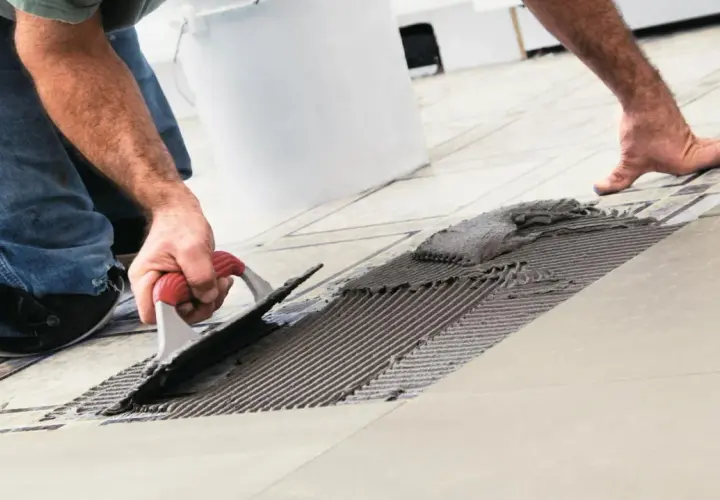 Uomo con spatola stende colla per piastrelle bagno fai da te. Nuove piastrelle in posa.