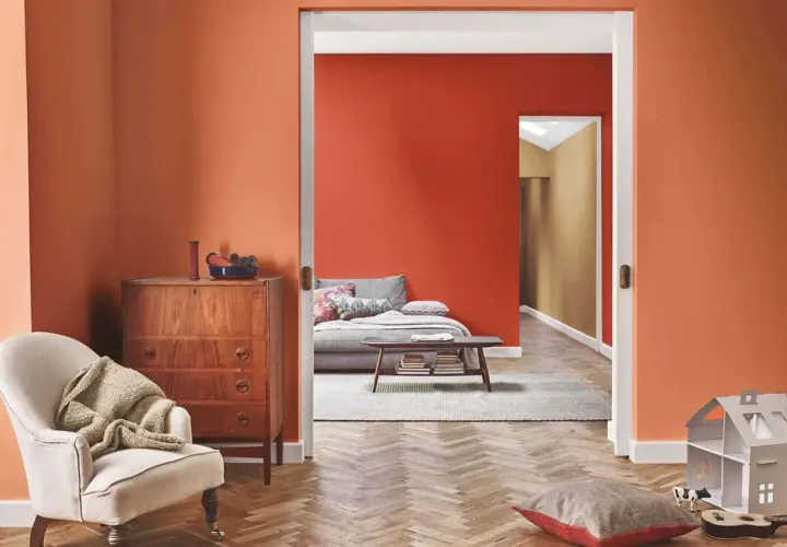 Un soggiorno accogliente con pareti arancioni, un divano letto e un mobile vintage. Perfetto per chi vuole imbiancare casa con stile.