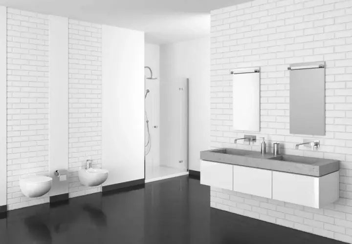 Bagno moderno con pavimenti in resina scura, sanitari sospesi, doccia a scomparsa e doppio lavabo in cemento.