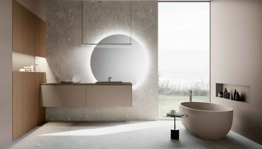 Bagni moderni con eleganti piastrelle effetto pietra. Vasca ovale, mobile sospeso e specchio luminoso creano un'oasi di relax.