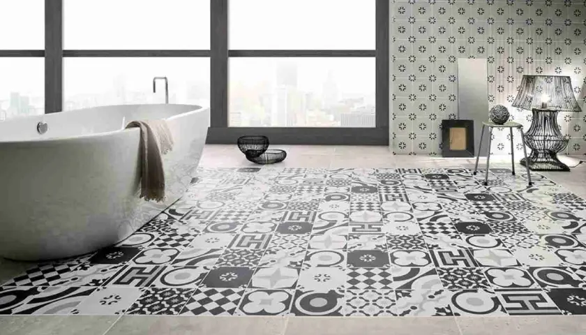 Bagno moderno con vasca freestanding e pavimento decorato con cementine in bianco e nero, che creano un effetto visivo unico.