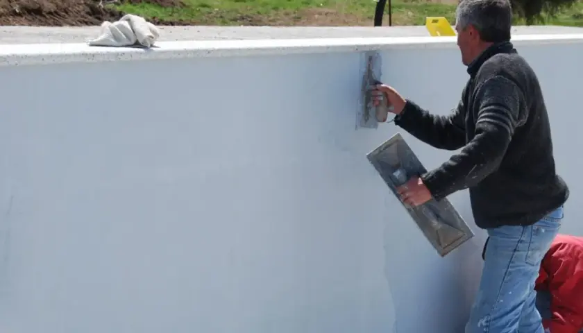 Operaio stende malta bastarda su un muro. Questo materiale serve per intonaci e murature, garantendo resistenza e durabilità.